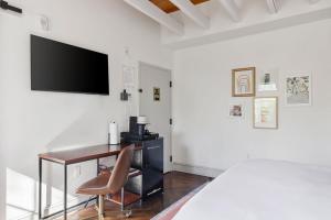 a bedroom with a desk and a television on a wall at 4th Floor Queen Suite Boutique hotel in Savannah