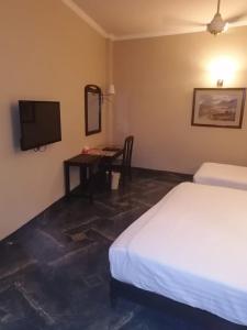 a bedroom with a bed and a desk with a television at Hotel Grand Peshawar in Peshawar