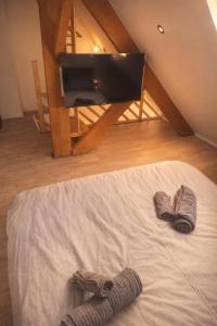 a bed with a pair of slippers and a tv at Au Carnot in Douai