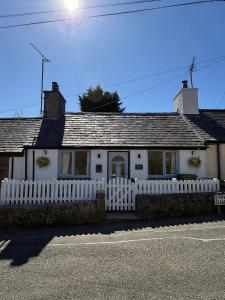 a white house with a white picket fence at Sandytoes Cottage in Pentraeth