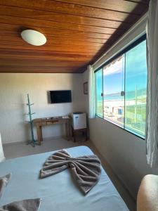 a bedroom with a bed with a large window at Pousada Casa do Telhado Verde in Cabo Frio