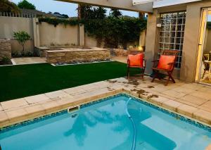 a swimming pool in a yard with two chairs and aificialificialificialificialificial at Bonne Esperance in Tyger Valley