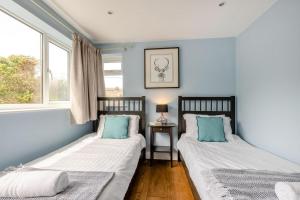 two beds in a room with two windows at 4 Bed in Braunton oc-56111 in Croyde