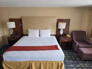a hotel room with a large bed and a chair at Wolcott inn and suites in Wolcott