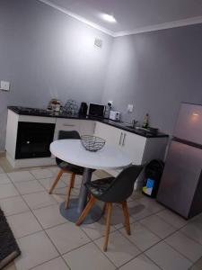 a kitchen with a table and two chairs and a refrigerator at Fullmoon Homes 9A in Edenvale