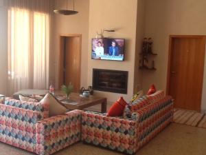 a living room with two couches and a tv on the wall at DOMAINE VILLa in Tameslouht +2 photos