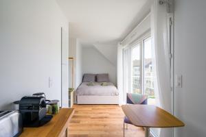 a small white room with a bed and a table at Studio de la Plage des Dames - À 50 m de la plage in Douarnenez