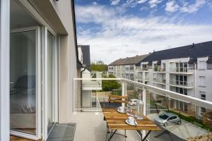 a balcony with a wooden table and a view of a building at Studio de la Plage des Dames - À 50 m de la plage in Douarnenez +4 photos