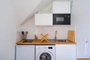 a kitchen with a washing machine and a microwave at Studio de la Plage des Dames - À 50 m de la plage in Douarnenez