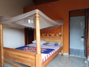 a wooden bed with a canopy in a room at Aunties Resort - Orutindo Kids Tantenlodge in Muhanga