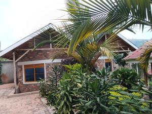 a house with a palm tree in front of it at Aunties Resort - Orutindo Kids Tantenlodge in Muhanga