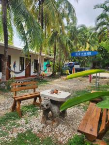 a picnic table and benches in front of a resort at Don Jon's Surf and Yoga Lodge in Santa Teresa Beach