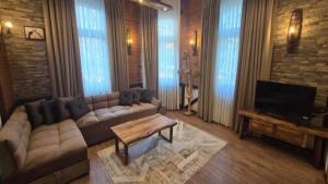 a living room with a couch and a tv at Къща за гости Велчева Завера in Samokov
