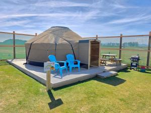 a yurt with two chairs and a table and a picnic table at Rainbow's End Yurts in Dornoch