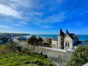 an old house on a hill next to the ocean at LE RUBAN BLEU FACE A LA MER in Arromanches-les-Bains