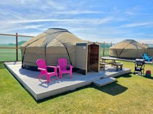 a yurt with two pink chairs and a table and a bench at Rainbow's End Yurts in Dornoch