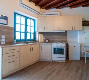 a kitchen with wooden cabinets and a white stove top oven at Alexandra House in Kimolos