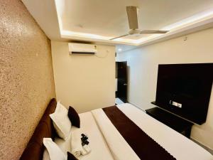a hotel room with a bed and a flat screen tv at Hotel MK in Ratlām