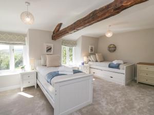 two beds in a white room with windows at Barn Howe in Kendal