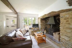 a living room with a leather couch and a fireplace at Lavender Cottage in Gillingham