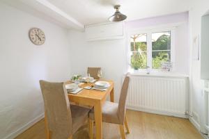 a dining room with a table and chairs and a clock at Lavender Cottage in Gillingham +10 photos