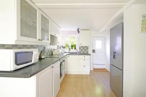 a kitchen with white cabinets and a microwave at Lavender Cottage in Gillingham