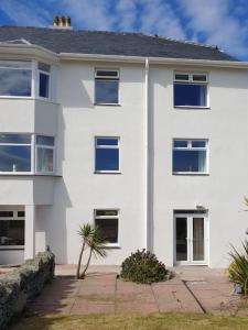 a white house with blue windows and a courtyard at Cwtch y Môr - NEW Outdoor Pool Spacious 3 bed, sea & mountain views in Holy Island