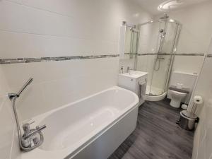 a white bathroom with a tub and a toilet at Cwtch y Môr - NEW Outdoor Pool Spacious 3 bed, sea & mountain views in Holy Island