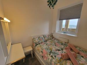 a small bedroom with a bed and a window at Cwtch y Môr - NEW Outdoor Pool Spacious 3 bed, sea & mountain views in Holy Island +18 photos
