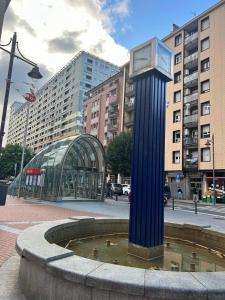a blue clock tower in a fountain in a city at Centrico tu hogar en Bilbao in Barakaldo