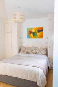 a bedroom with a white bed with a painting on the wall at Inisfail in Killarney