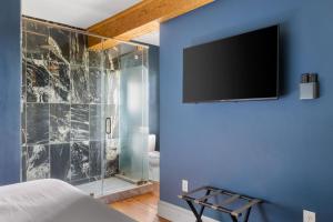 a bathroom with a shower and a television on a wall at King Suite 4th Floor Downtown Hotel Boutique in Savannah +15 photos