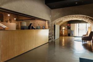 a woman is standing at a counter in a room at URH - Hotel Molí del Mig in Torroella de Montgrí +56 photos