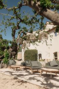 a group of picnic tables and chairs under a tree at URH - Hotel Molí del Mig in Torroella de Montgrí