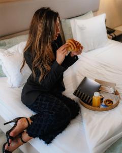 a woman sitting on a bed eating a doughnut at My Charm Lisbon Suites in Lisbon
