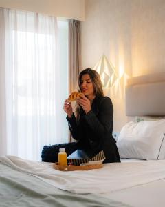 a woman sitting on a bed eating a sandwich at My Charm Lisbon Suites in Lisbon