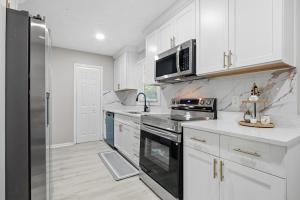 a kitchen with white cabinets and a stainless steel refrigerator at Elegant Modern Ranch Home in Atlanta