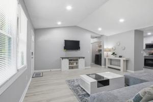 a white living room with a couch and a tv at Elegant Modern Ranch Home in Atlanta