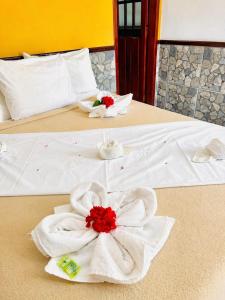 two beds with white towels and red flowers on them at Pousada H&D in Angra dos Reis