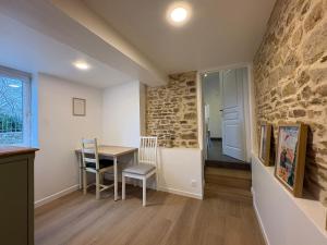 a dining room with a table and a stone wall at Clécy Chouette maison atypique centre in Clécy
