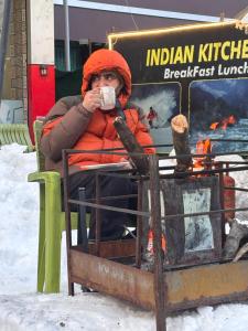 a person sitting in a chair drinking from a cup at Village guesthouse in Srinagar