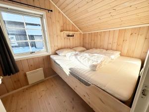 a bed in a wooden room with a window at Trysilbua 1173 in Trysil
