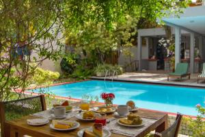 a table with food on it next to a swimming pool at Villa dos Graffitis Pousada in Morro de São Paulo