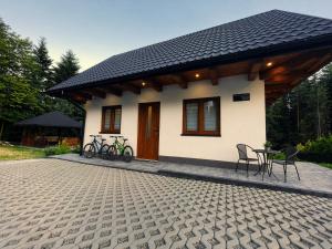 a small house with a table and chairs in front of it at Biały Domek Świerczek - Jacuzzi, Balia Ruska SPA, Rowery, Altana i Grill w Słopnice in Słopnice