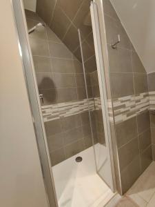 a shower with a glass door in a bathroom at LE RUBAN BLEU FACE A LA MER in Arromanches-les-Bains