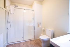 a white bathroom with a shower and a toilet at Dairy Green Flat in Shifnal