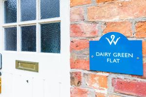 a blue sign on a brick wall next to a white door at Dairy Green Flat in Shifnal