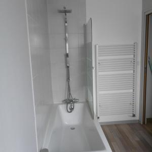 a white bath tub with a shower in a bathroom at Ker valou in Hénansal