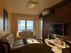 a living room with a couch and a television at Przno Sea Pearl - Seaview Holiday apartment in Pržno