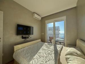 a bedroom with a bed and a tv and a balcony at Przno Sea Pearl - Seaview Holiday apartment in Pržno